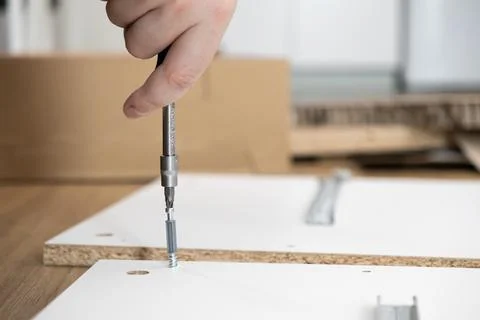 A person's hand precisely guides a screwdriver to assemble flat-pack furnit.. Stock Photos