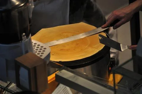 A person's hand preparing the dough to make a crepe, food business Stock Photos