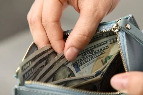 Persons hand pulling out united states dollar bills from a light blue wallet, Stock Photos