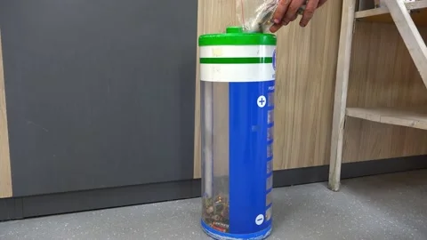 The person's hand puts used batteries in the recycling container. 動画素材 153747722