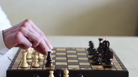 A person's hand reaches out to move a white pawn on a chessboard Stock Footage 278900475