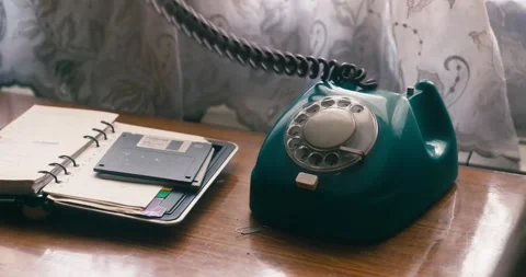 Person’s hand is reaching out to pick up a teal rotary phone placed next Stock Footage 274250016