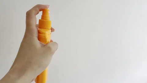 Person's hand repeatedly spraying a yellow bottle of sunscreen or cosmetic .. Vídeos de archivo 335139396