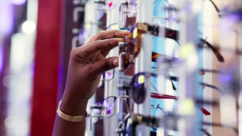 Person's hand selecting sunglasses from a rack in an optical store Stock Footage 346771207