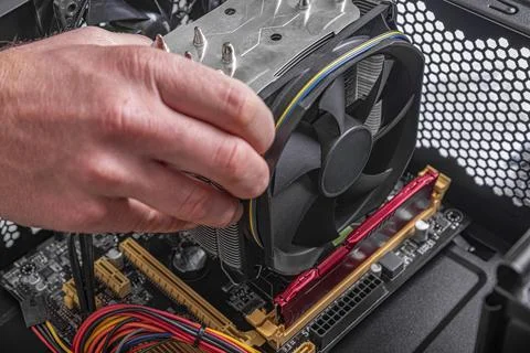 A persons hand is shown installing CPU cooler onto a motherboard inside a Stock Photos
