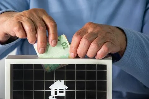 A persons hand is shown placing a twenty euro bill into a donation box with.. Stock Photos