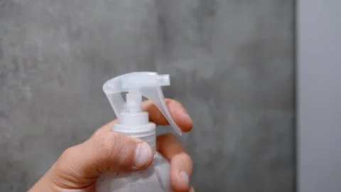 Person's hand spraying liquid from a transparent plastic bottle Stock Footage 330081342