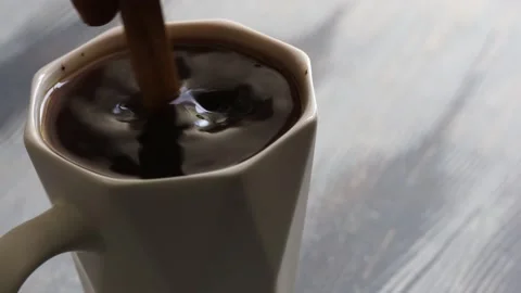 A person's hand stirs a cup of coffee with a wooden spoon Stock Footage 185071137