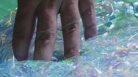 A person's hand is touching a piece of plastic that is floating in the water Video stock 274859990