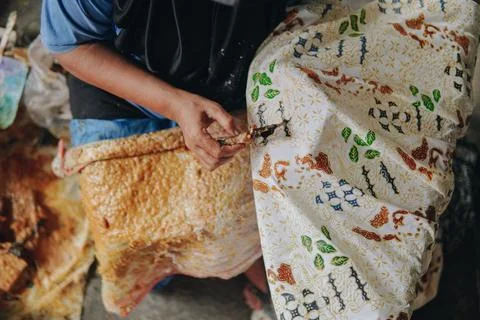 Person's hand is tracing design the pattern of batik tulis cloth using Cantin Stock Photos