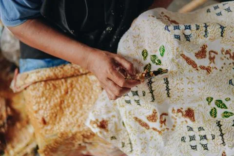 Person's hand is tracing design the pattern of batik tulis cloth using Cantin Stock Photos