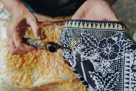 Person's hand is tracing design the pattern of batik tulis cloth using Cantin Stock Photos