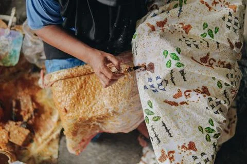 Person's hand is tracing design the pattern of batik tulis cloth using Cantin Stock Photos