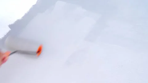 A person's hand using an orange paint roller to apply a fresh layer of grey.. Stock Footage 333602872