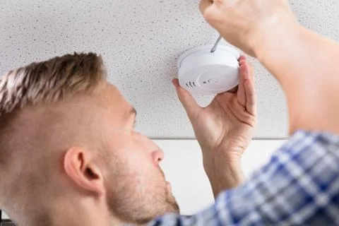 Person's Hand Using Screwdriver To Install Smoke Detector Stock Photos