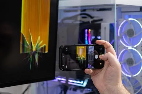 Person's hand using a smartphone to photograph a severely cracked computer .. Stock Photos