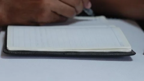 Person's hand writing notes in a lined notebook Stock Footage 345741048