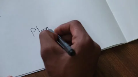 Person's hand writing the word "Plan" with a black pen on a blank white sheet Видео 330480349