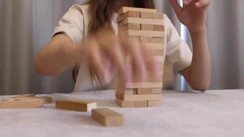 A person's hands are shown solving a wooden block puzzle, concentrating on Stock Footage 278889937