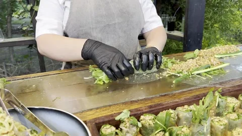 Person's hands in black gloves wraps up roll  with greens Stock Footage 245340099