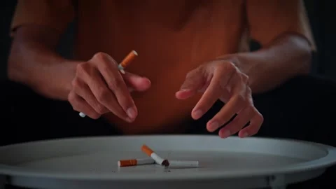 Person's hands break a cigarette in half for symbolizing quitting smoking Stock Footage 316887546