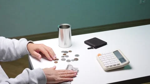 Person's hands carefully counting a small stack of coins and a crumpled dollar Stock Footage 345170427