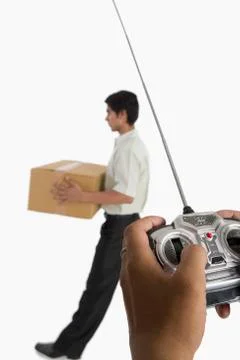 Person's hands controlling a worker with a remote control Фото