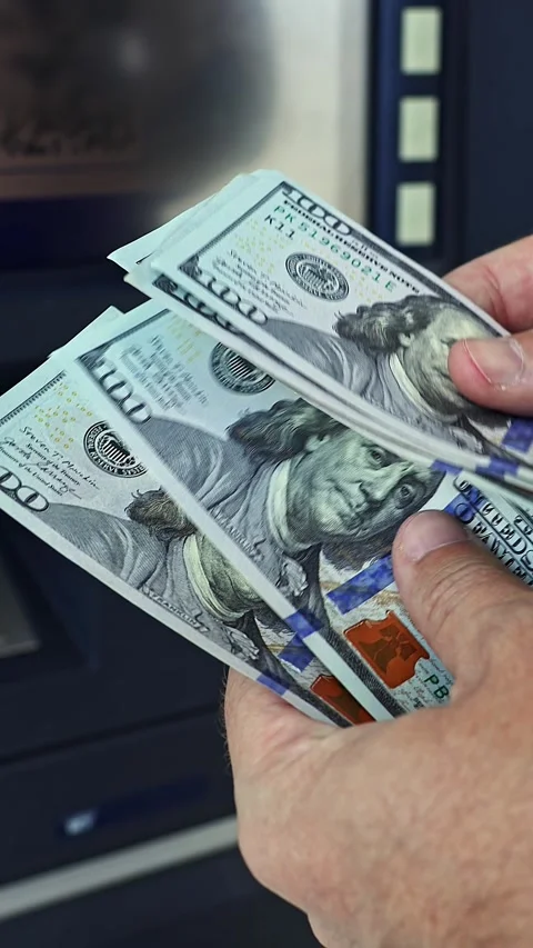 Person's hands count 100 american dollar banknotes near ATM machine Stock Footage 336663689