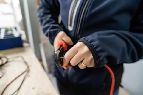 Person's hands crimping electrical wire connector in workshop Stock Photos