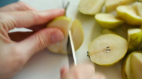 Persons hands cutting fresh green pear with knife on white board Video stock 321737036