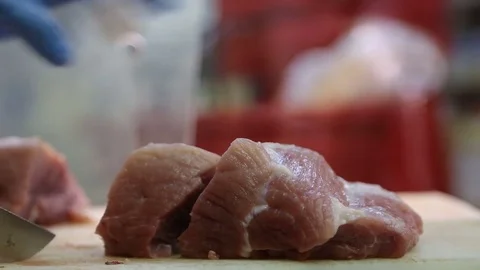 Person's hands cutting a large piece of raw meat using a butcher's knife Stock Footage 73050877