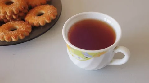 A person's hands dip a tea bag into a cup of hot water on a table with swee.. Stock Footage 318413732