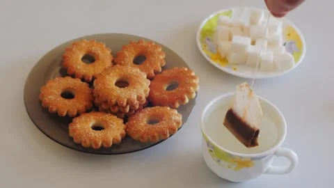 A person's hands dip a tea bag into a cup of hot water on a table with swee.. Stock Footage 329505859