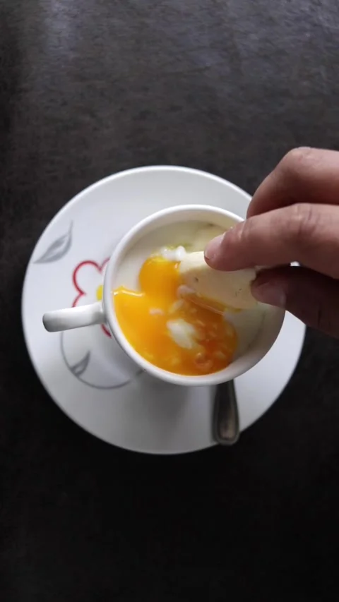 A person's hands dipping a piece of bread into a cup of hard-boiled eggs 動画素材 345088541