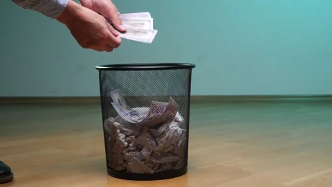 Person's hands dropping crumpled banknotes into a metal mesh garbage can Stock Footage 342765574