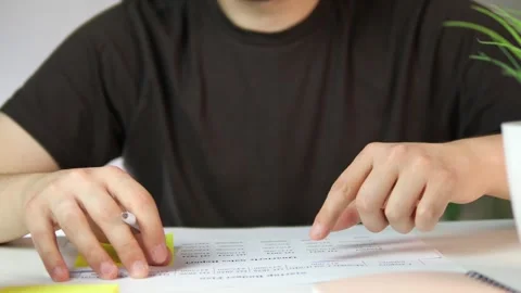 A persons hands engage with a structured printed table, fingers following the Stock Footage 316904953