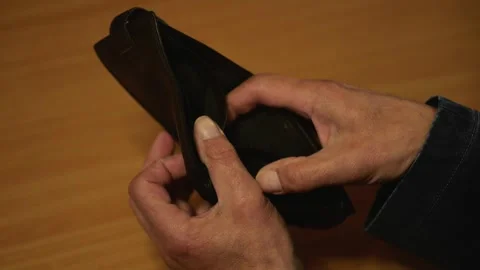 Person's hands examine empty wallet on wooden table at home. Stock Footage 336623558
