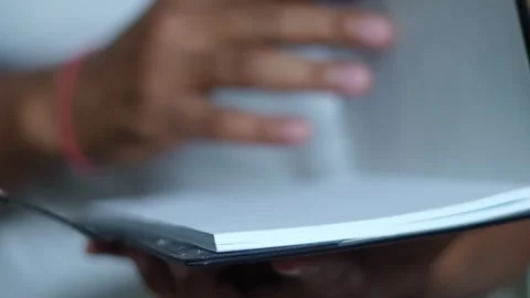 Person's hands flipping through pages of black leather notebook for writing Stock Footage 345189041