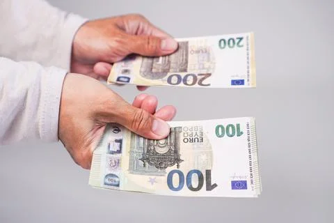 A person's hands holding and displaying two separate stacks of Euro banknot.. Stock Photos