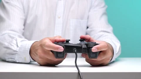 Person's hands holding a black wired gamepad controller, engaging in gameplay Stock Footage 342767981