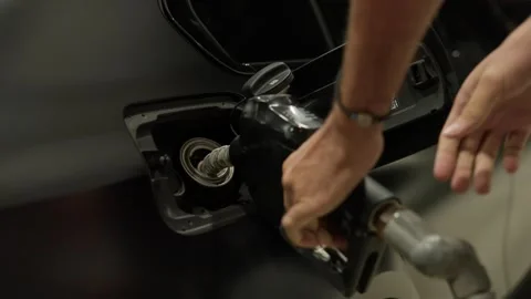 Person's hands holding a gas pump nozzle, refueling a black car at a station Stock Footage 341958075