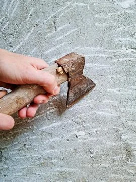 A person's hands holding a rusty axe with a wooden handle. Stock Photos