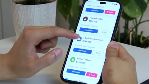 A persons hands interact with a mobile app, exploring dream homes and potential Stock Footage 315210608