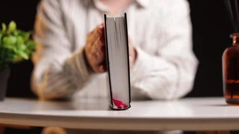 Person's hands interacting with a book on a table with decorative elements Stock Footage 339211831