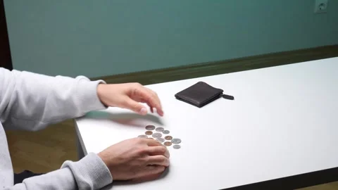Person's hands meticulously counting a small pile of coins on a white table Stock Footage 346251025