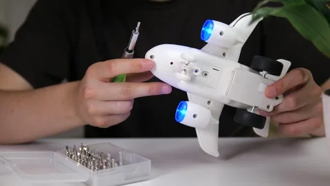 A persons hands meticulously test the operational features of a toy plane after Stock Footage 315175438