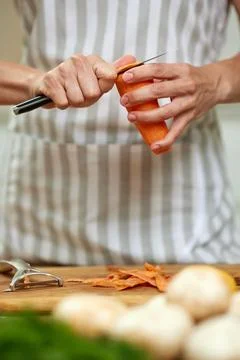 Person's hands peeling fresh carrot preparing healthy meal 写真素材