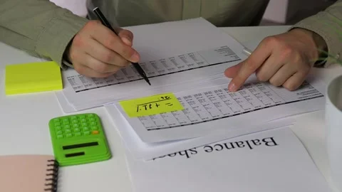 A persons hands perform calculations based annotated financial documents, adding Stock Footage 316296864