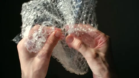 Person's hands popping bubble wrap for stress relief 動画素材 337830370