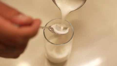 Person's hands pouring a creamy fermented milk drink into a glass Stock Footage 336734649